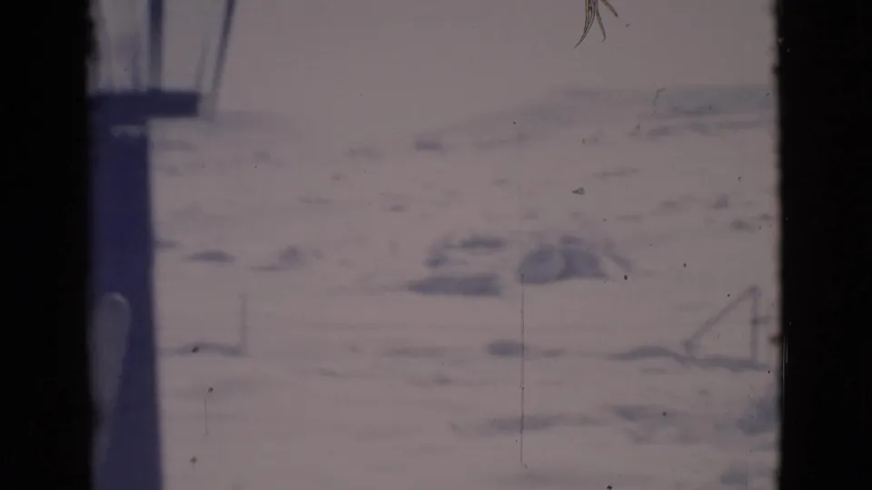 1966 Clarkdale, Arizona frame with pale snowy ground, faint low structures or rails, and dark vertical borders from the filming position.
