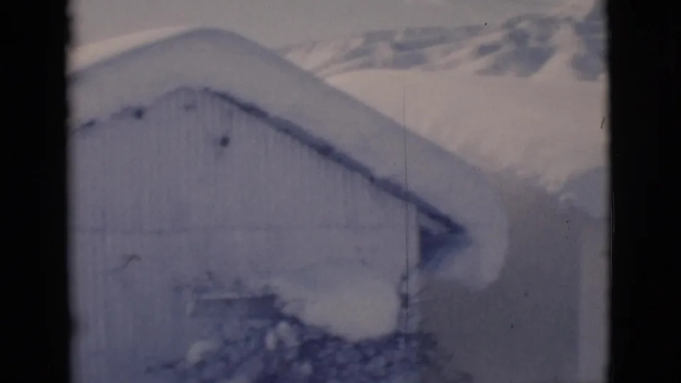 1966 Clarkdale, Arizona frame showing a snow-laden roofline, corrugated wall, and accumulated drifts around a small structure.