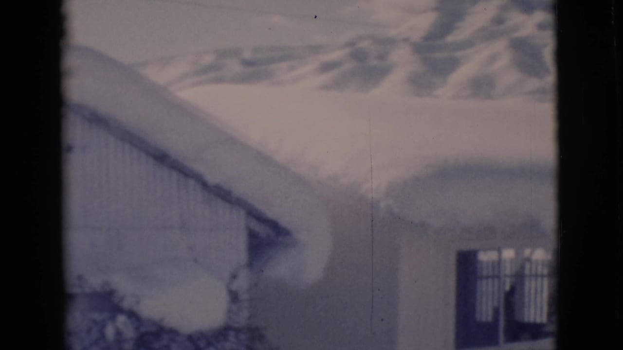Snow-covered building with distant hills and dark film borders.