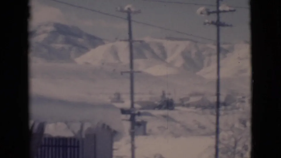 1966 Clarkdale 8mm frame with utility poles, power lines, snow-covered ground, and low hills in the distance.