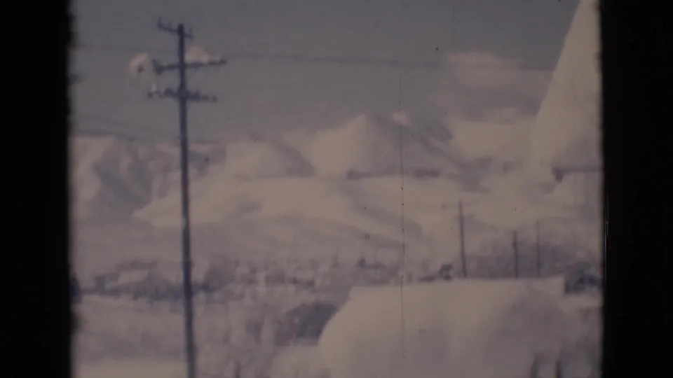 1966 Clarkdale, Arizona home-movie frame showing snowy hills, power poles, and overhead lines in a muted winter view.