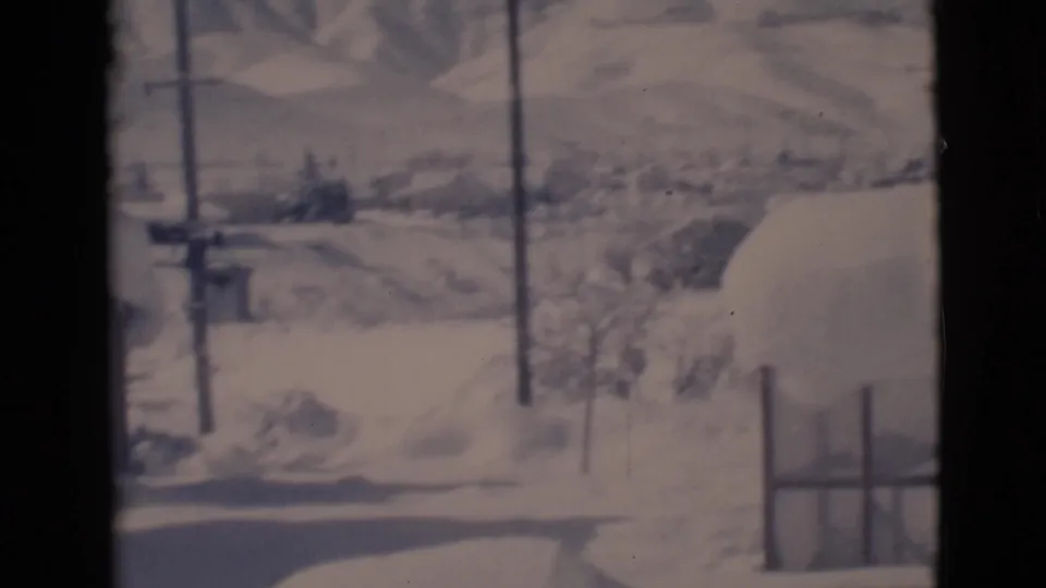 1966 Clarkdale winter view with utility poles, a snow-lined road or path, fencing, and low hills in the background.