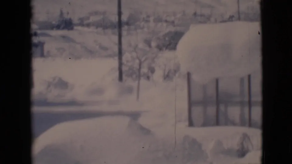Final 1966 Clarkdale frame showing a snow-laden building edge, fence, utility pole, and muted hillside landscape.