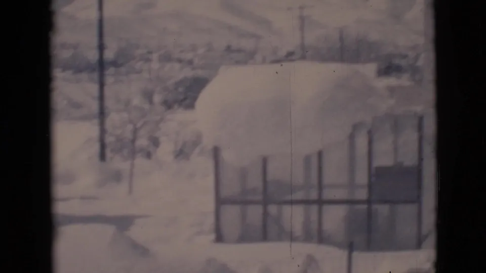 Clarkdale, Arizona 1966 frame showing a snowy yard, fence, bare trees, and a bundled adult partly visible near the bottom edge.