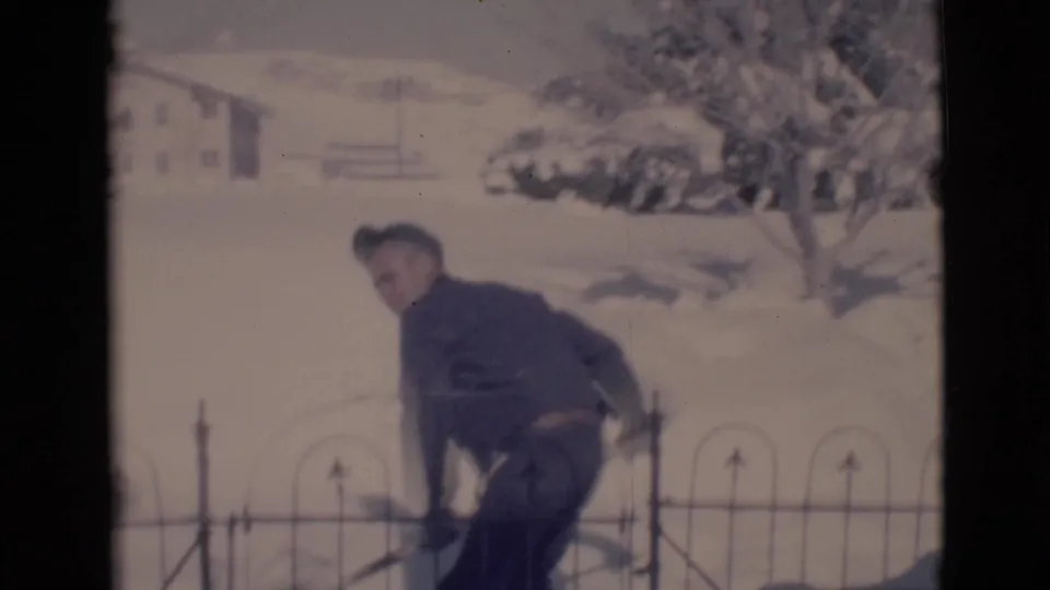 In Clarkdale, Arizona, 1966, a youth in a dark jacket bends with a snow shovel near a wrought-iron fence in a snowy residential yard.