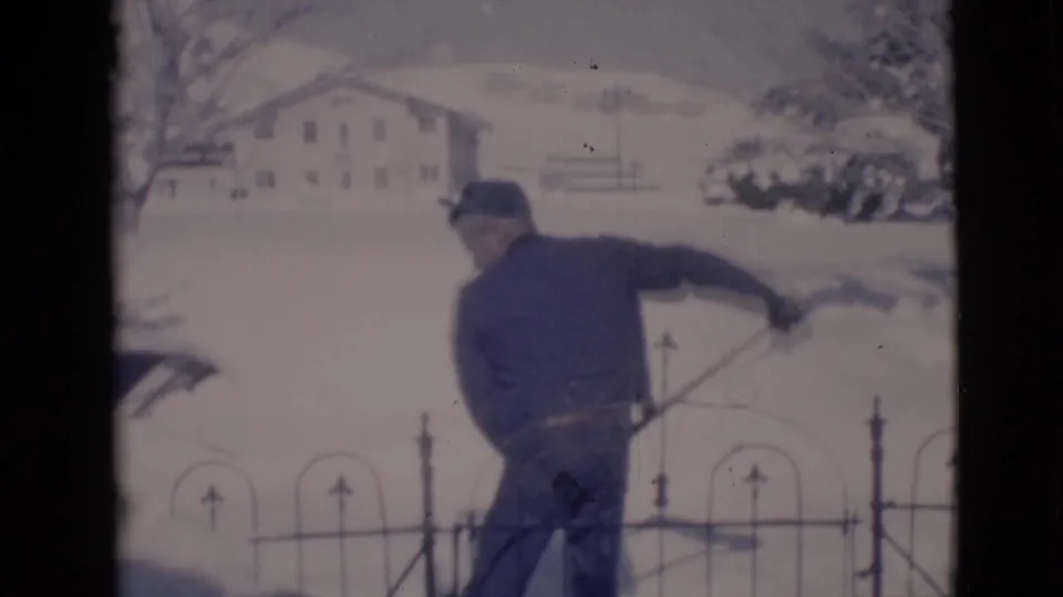 The youth swings the shovel outward in the snowy Clarkdale yard, suggesting a throw of snow toward or near the camera.