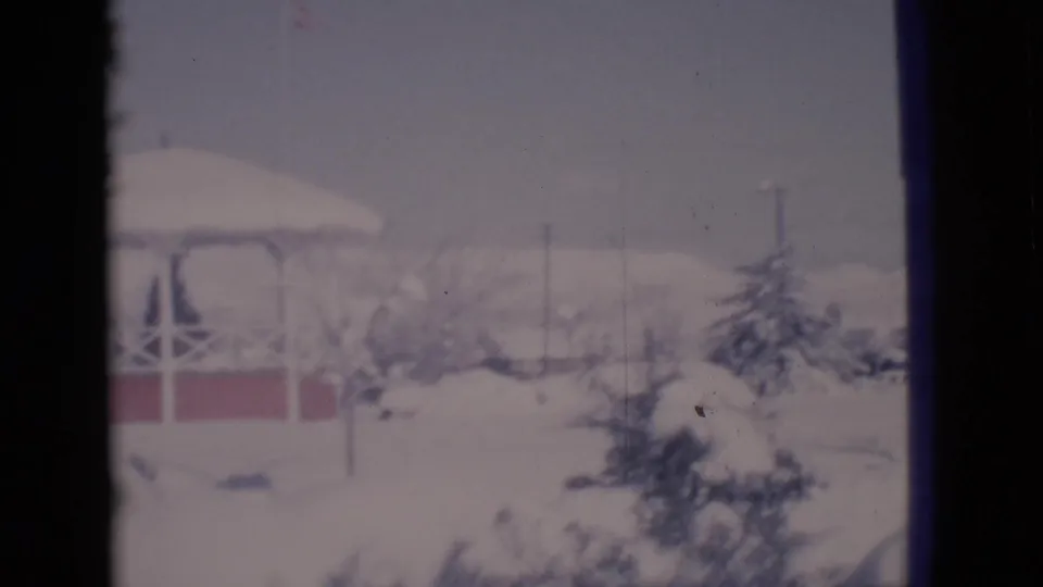 1966 Clarkdale, Arizona 8mm frame showing the gazebo partly cropped beside snow-covered evergreen shrubs and open snowy ground.