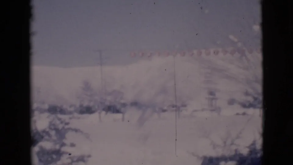 1966 Clarkdale, Arizona frame showing a snowy town view with bare trees, utility poles, low buildings, and a distant hillside.