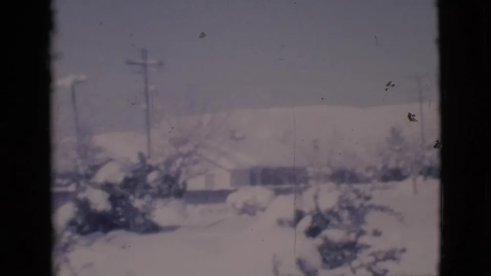 A Clarkdale winter neighborhood appears beyond the window, with snowy roofs, trees, and utility poles softened by 8mm film texture.