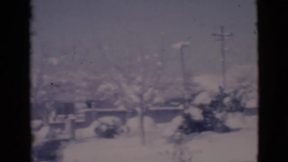 The 1966 Clarkdale home movie view shows snow-covered trees, low houses, and a utility pole through a dark window frame.