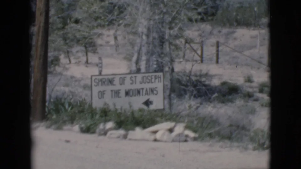 Clarkdale, Arizona home-movie frame showing the Shrine of St Joseph of the Mountains roadside sign in bright sun.