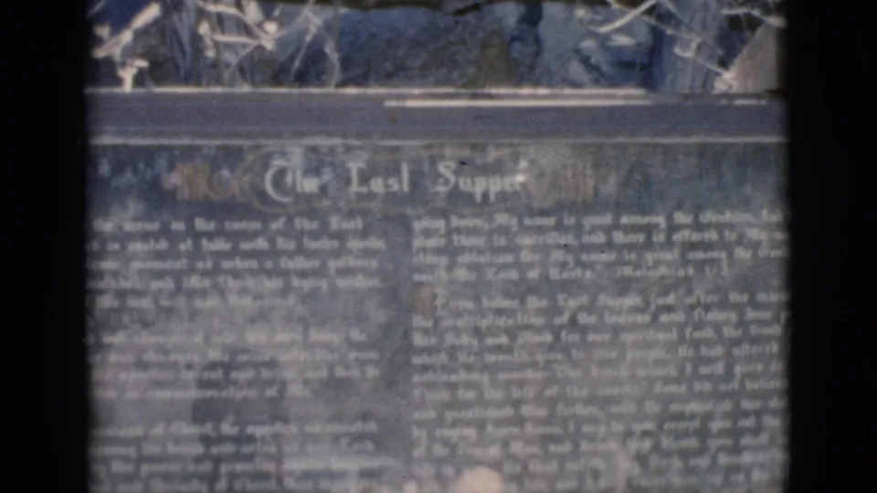 1966 home-movie frame holding on the Last Supper interpretive sign, with soft focus and visible 8mm texture.