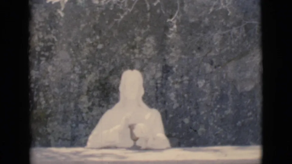 1966 Clarkdale, Arizona frame showing a white seated religious figure against a rough stone wall after the marker shot.