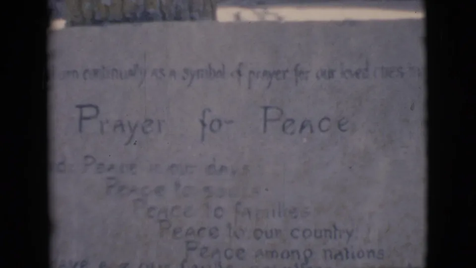 1966 Clarkdale home-movie frame showing a handwritten Prayer for Peace note on a pale textured background.