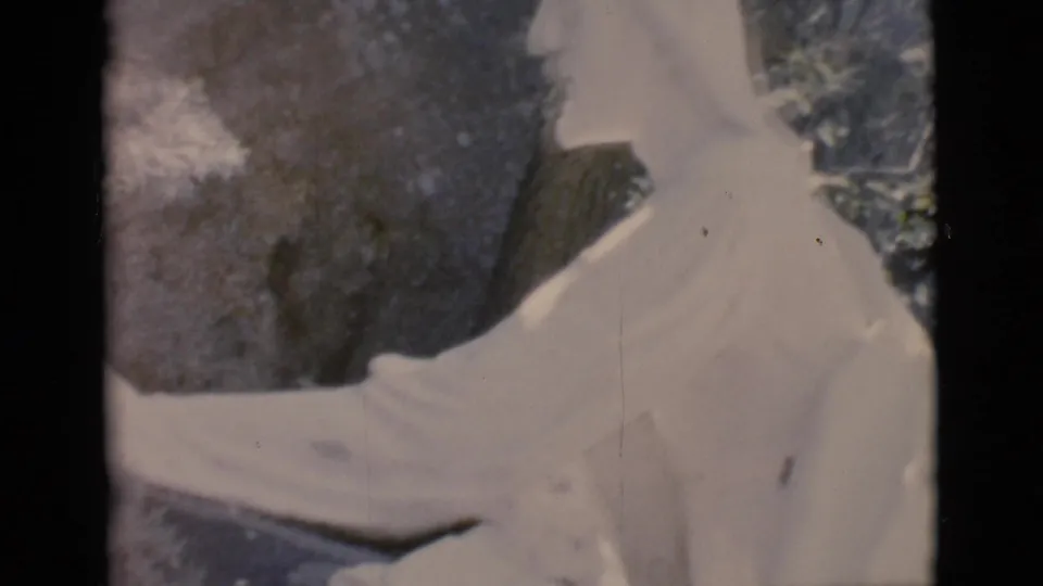 1966 Clarkdale, Arizona 8mm frame showing a white outdoor statue in profile with an extended arm, rocks, and trees behind it.