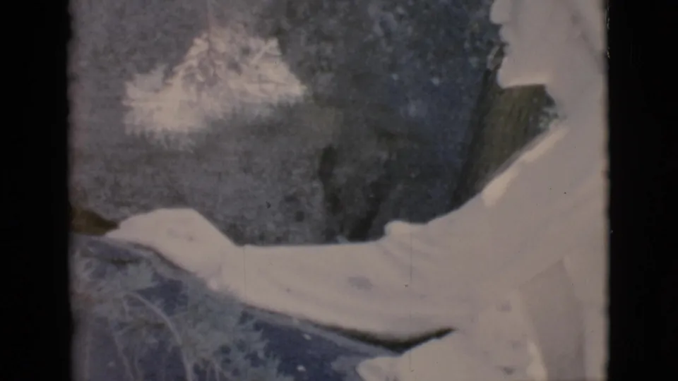 1966 Clarkdale, Arizona 8mm frame showing the white statue from a nearby angle, with its arm extending across rocks and outdoor brush.