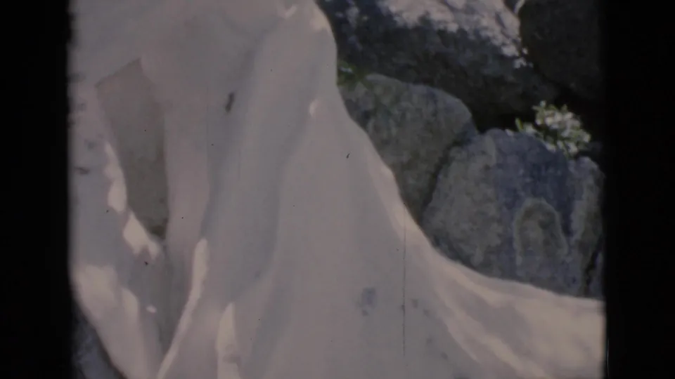 1966 Clarkdale, Arizona 8mm frame showing the white draped statue from a lower close angle with large rocks and trees in the background.