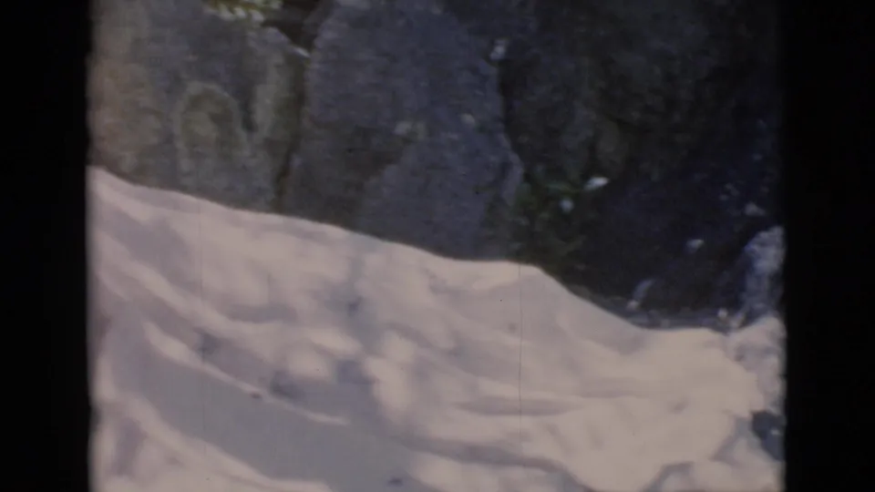 Final 8mm frame from Clarkdale, Arizona showing pale folded material at the base of shadowed rocks.
