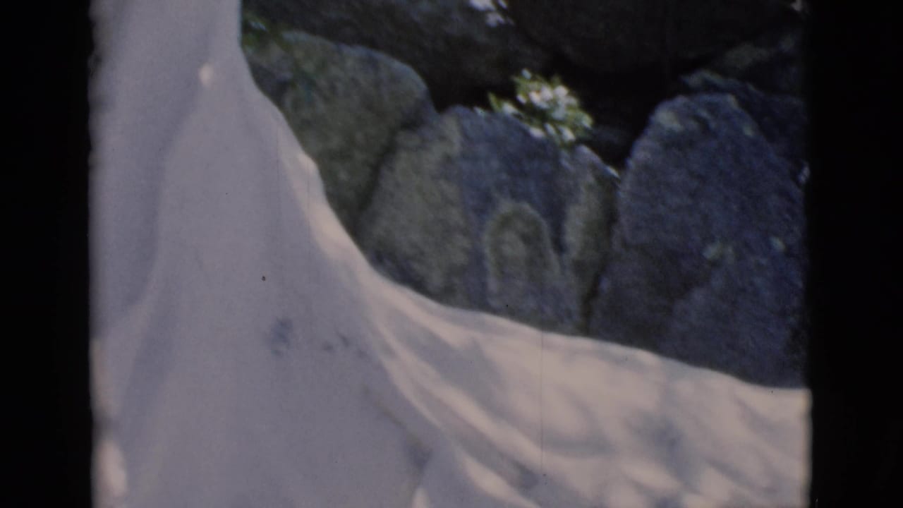 Close view of a white robed statue among rocks with dark film borders.