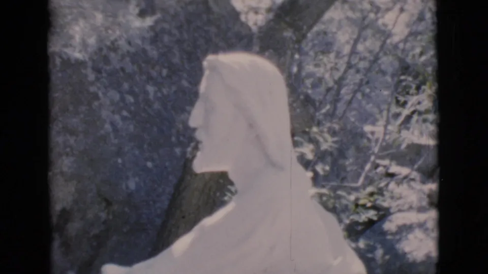 1966 Clarkdale, Arizona 8mm frame with the profile of a white robed religious figure against a rocky backdrop.