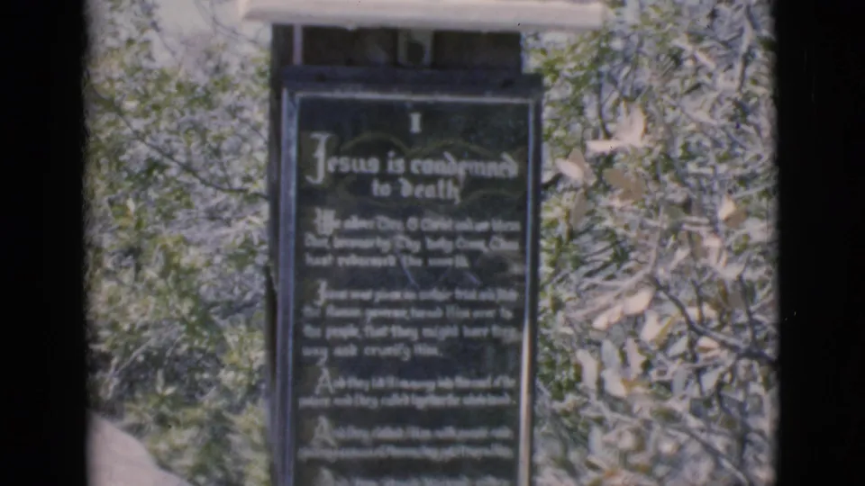 1966 Clarkdale 8mm frame showing a dark outdoor religious plaque about Jesus being condemned to death, with trees behind it.
