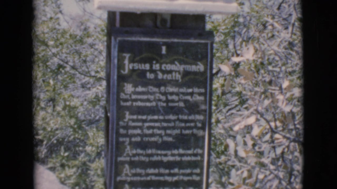 Dark religious plaque framed by trees and film-strip borders.