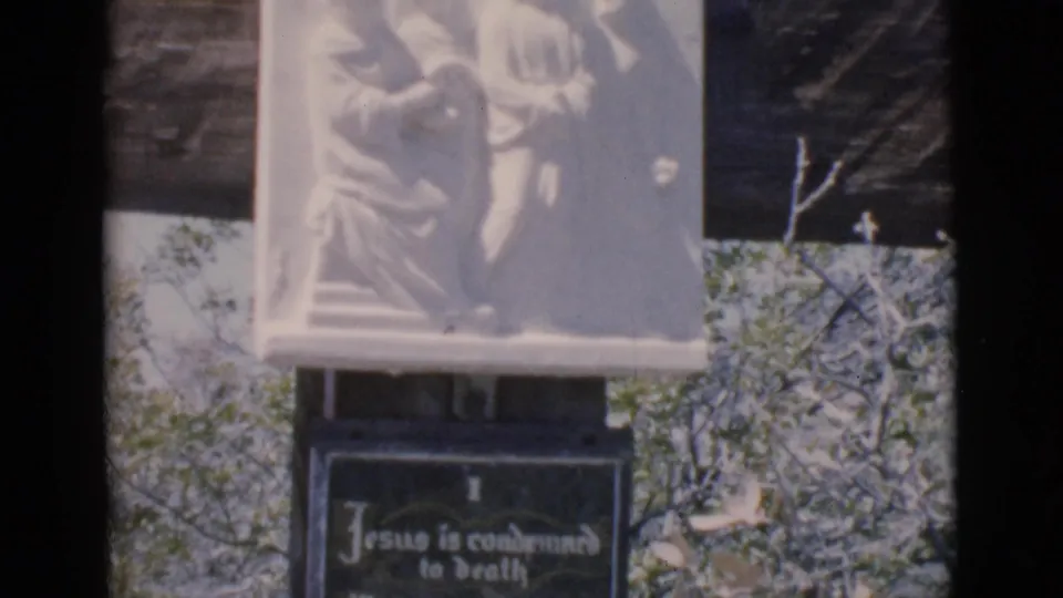 1966 8mm frame showing a white relief carving above the Jesus condemned to death plaque at an outdoor devotional display in Clarkdale.