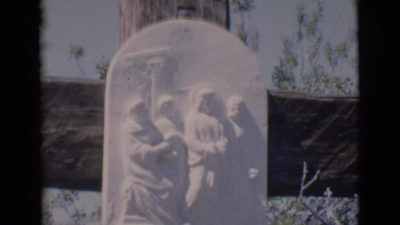 Close view of a religious relief plaque on a wooden cross.