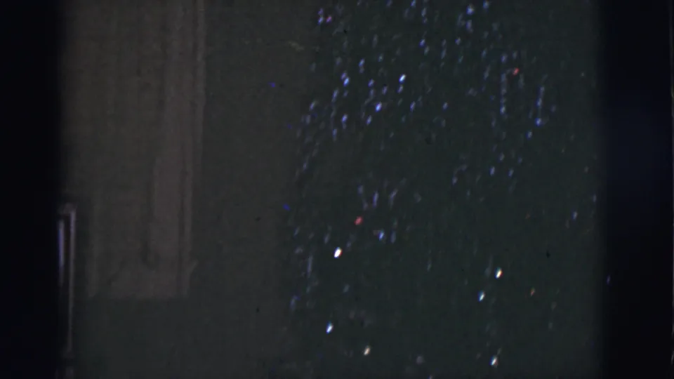 1966 Tucson 8mm frame showing a dark tree-like form with small colored lights and heavy underexposure.