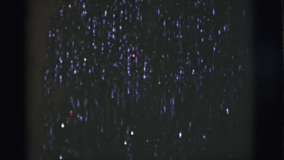 1966 8mm home-movie frame from Tuscon, Arizona showing scattered night-sky lights, grain, dust, and dark frame-edge shadows.