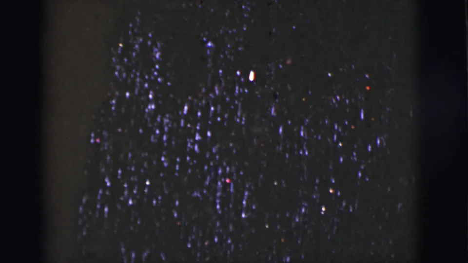 1966 Tuscon, Arizona 8mm frame showing a denser patch of night-sky lights, colored specks, grain, and dark gate-edge shadows.