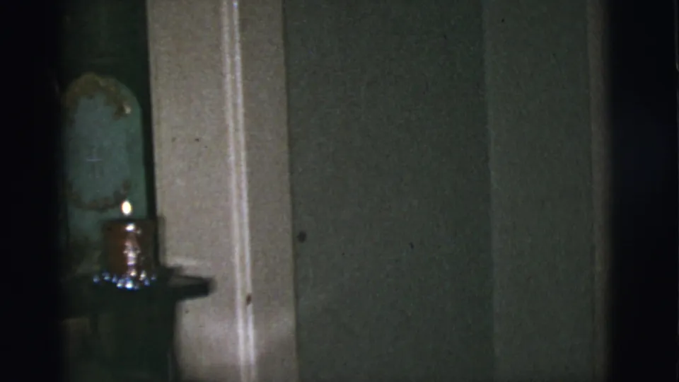 A dim 1966 Tucson interior shows part of a green religious shrine with a small lit candle near a doorway.