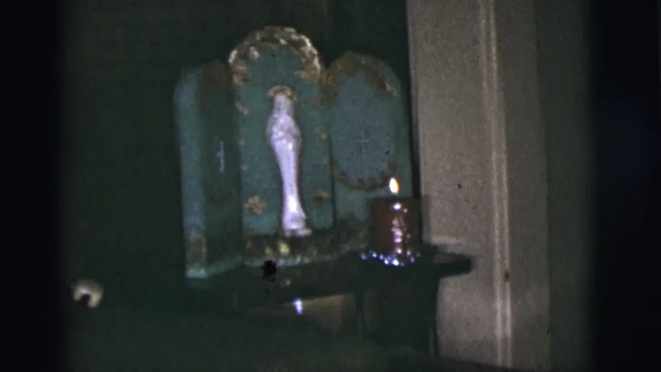 1966 Tuscon, Arizona home-movie frame showing a white Virgin Mary statue in a green shrine beside a burning candle.