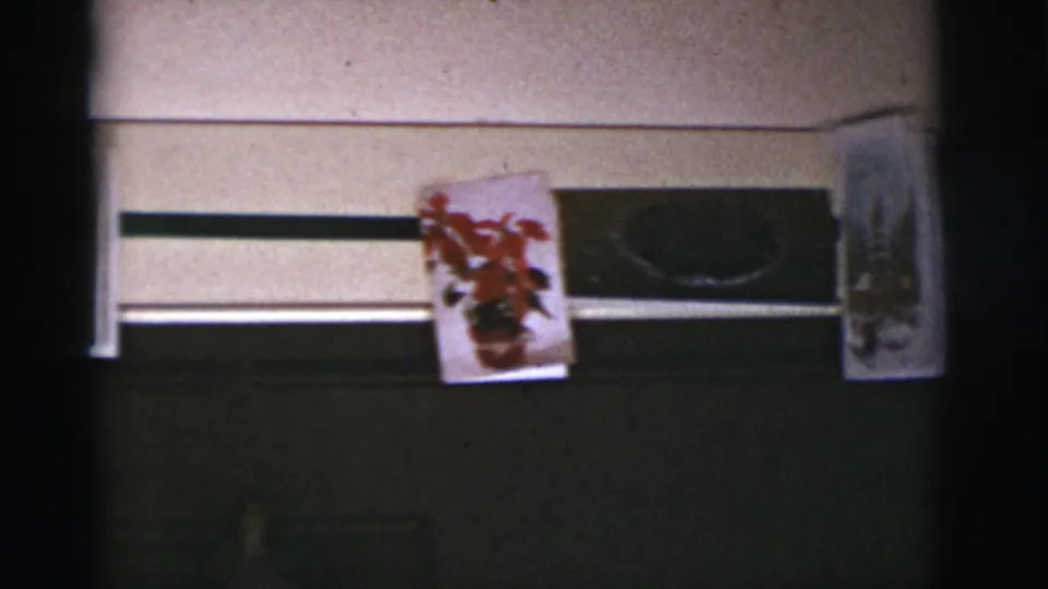1966 Tucson-area 8mm frame with a poinsettia Christmas card centered above a dark horizontal window or blackboard-like panel.