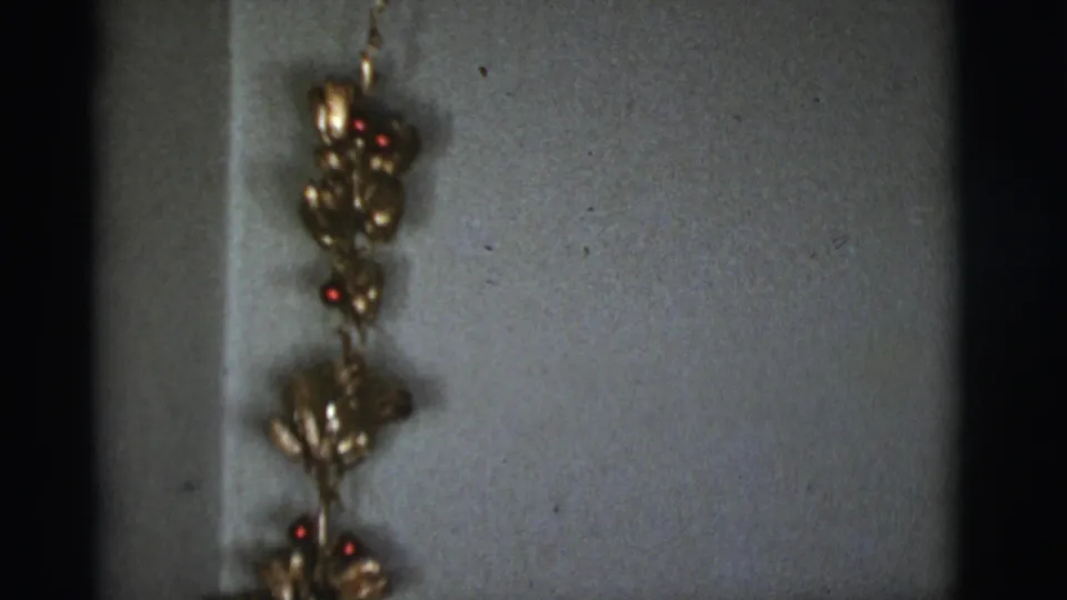 1966 home interior detail showing a hanging gold floral ornament with small red berries on a painted wall.