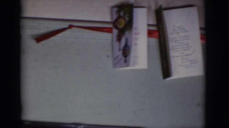1966 Tuscon frame showing a red ribbon and hanging Christmas cards on an interior wall.