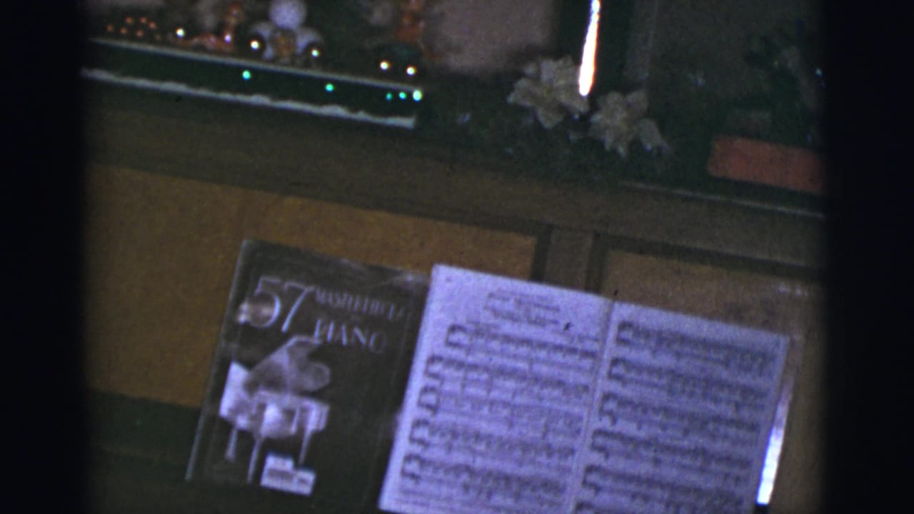 A piano music stand holds an open score and a book with a visible piano anthology cover.