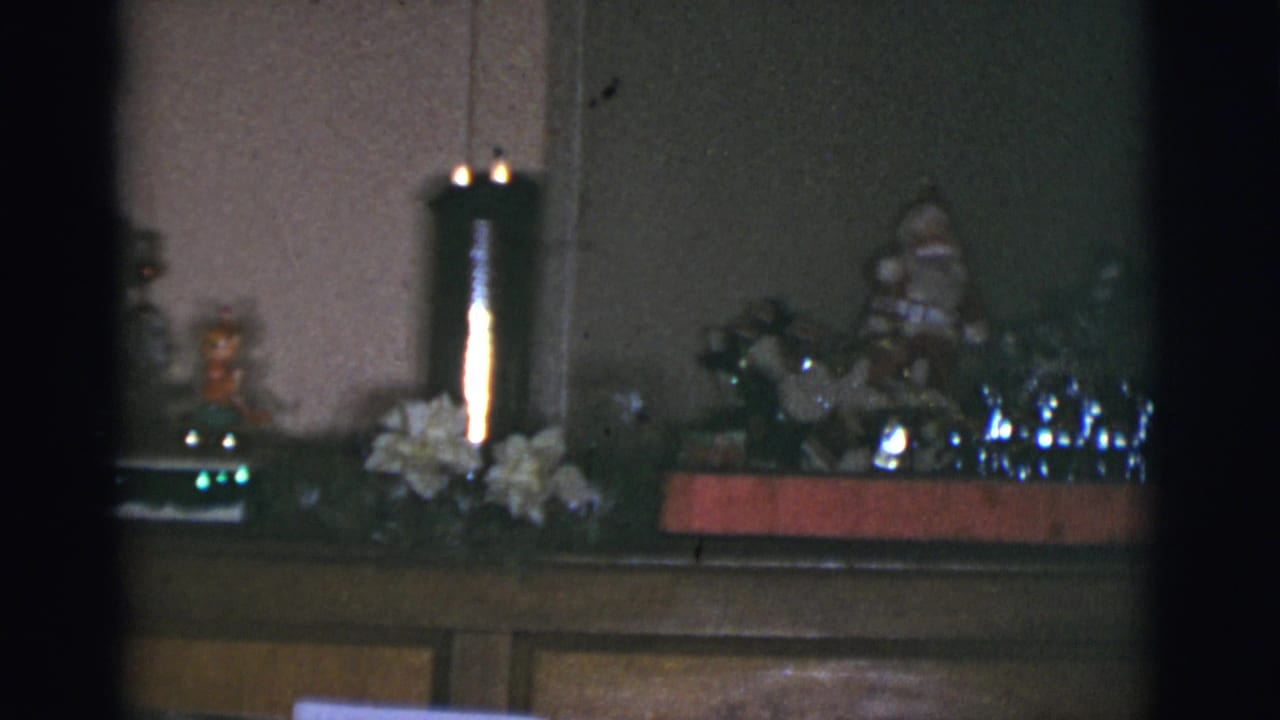 Piano top with a lit candle, white flowers, small figurines, and holiday ornaments.