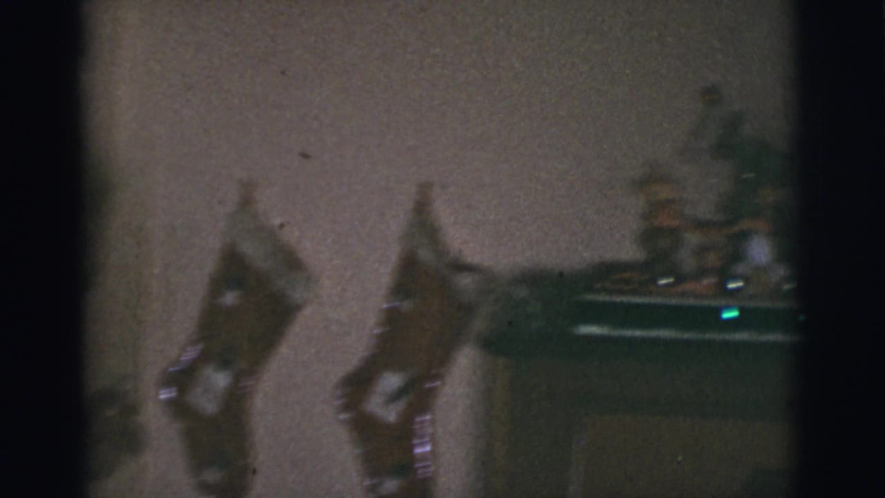 1966 Tuscon, Arizona 8mm frame showing a dim room wall with hanging stockings and a light-colored dog partly visible near the lower left.