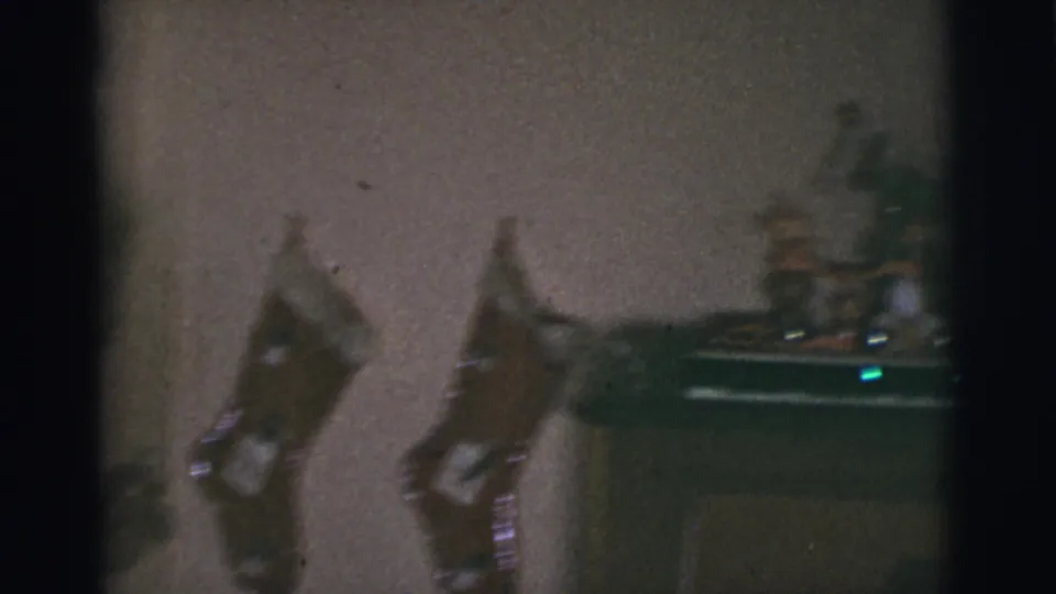 1966 Tuscon, Arizona 8mm frame showing a dim room wall with hanging stockings and a light-colored dog partly visible near the lower left.