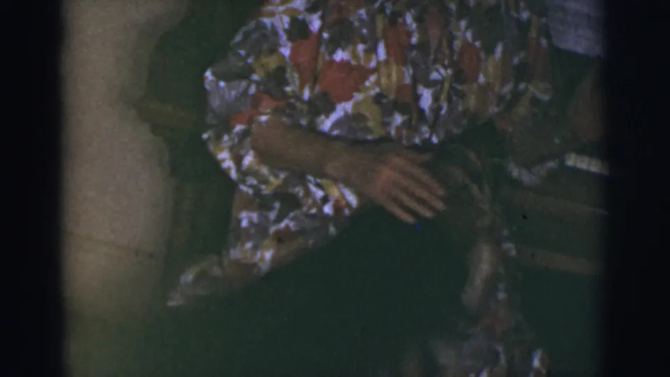 The woman remains seated in the Tucson home interior as the framing shifts toward her lap and the nearby piano area.