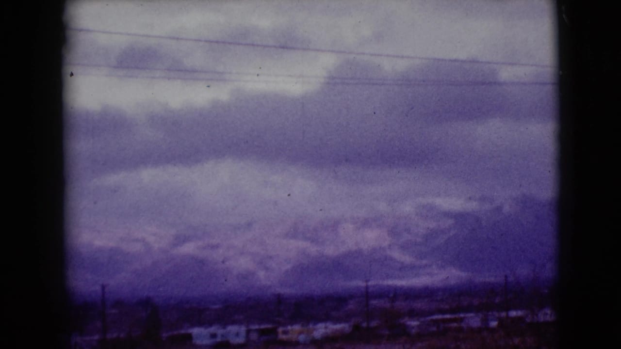 Cloudy mountain landscape with power lines and dark film-frame edges.