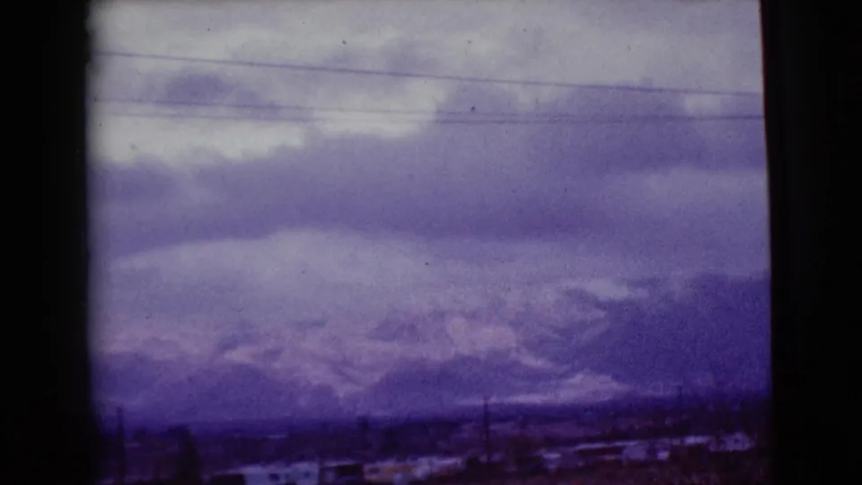 1968 Clarksdale, Arizona home-movie view of low clouds, hazy mountains, scattered structures, and roadside utility lines.