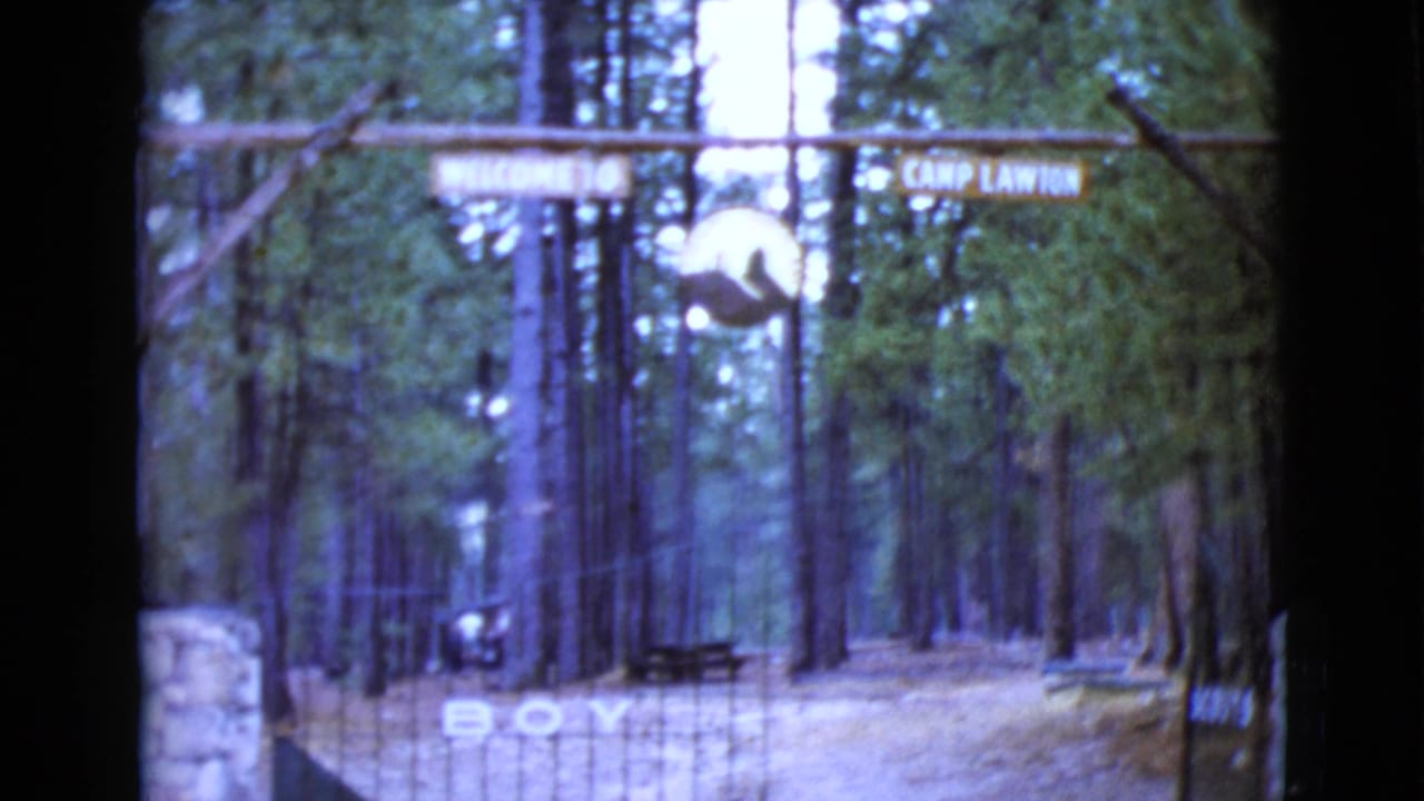 Wooden Camp Lawton welcome sign over a gated pine forest entrance.