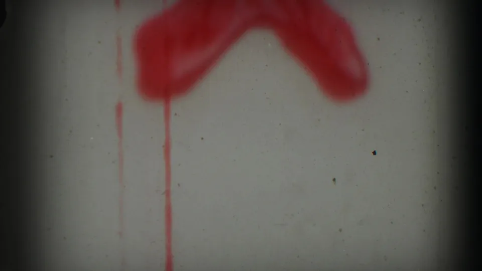Pale 8mm frame with red painted or leader markings, vertical red drips, dust, and a dark frame boundary.