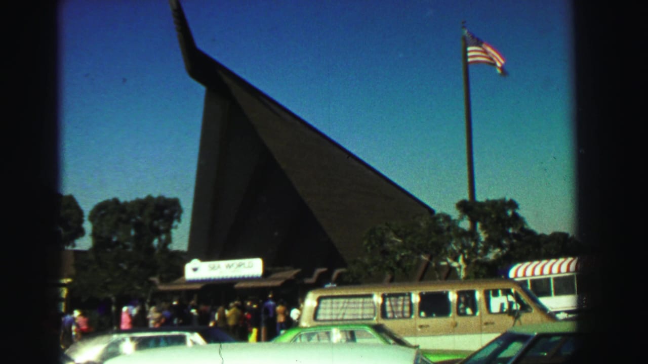 1969 Reno home-movie view of the Sea World entrance, with visitors gathered below a tall flagpole and pointed-roof structure.