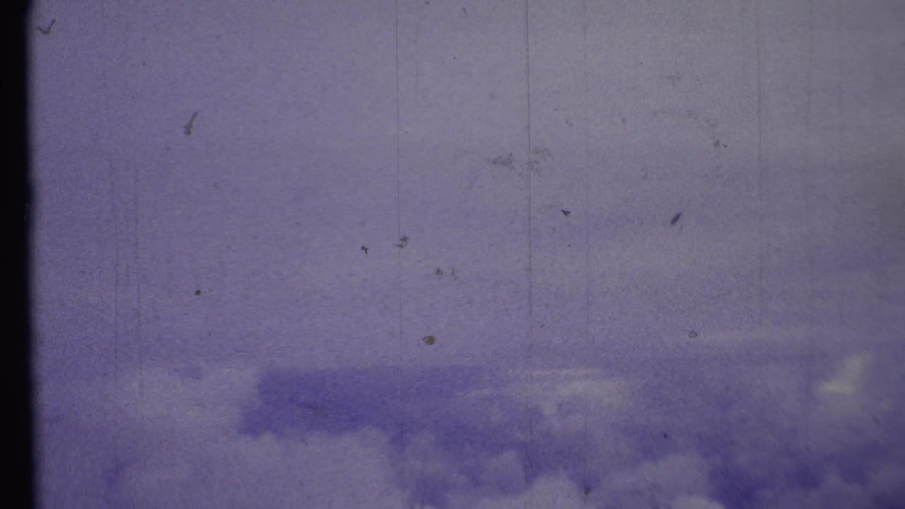 Cloudy blue sky with scratches, dust marks, and a dark vertical frame line.