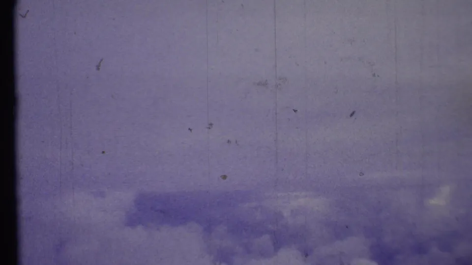 Clouds and blue sky appear in a soft 8mm frame, with scratches and a dark divider from the film scan.