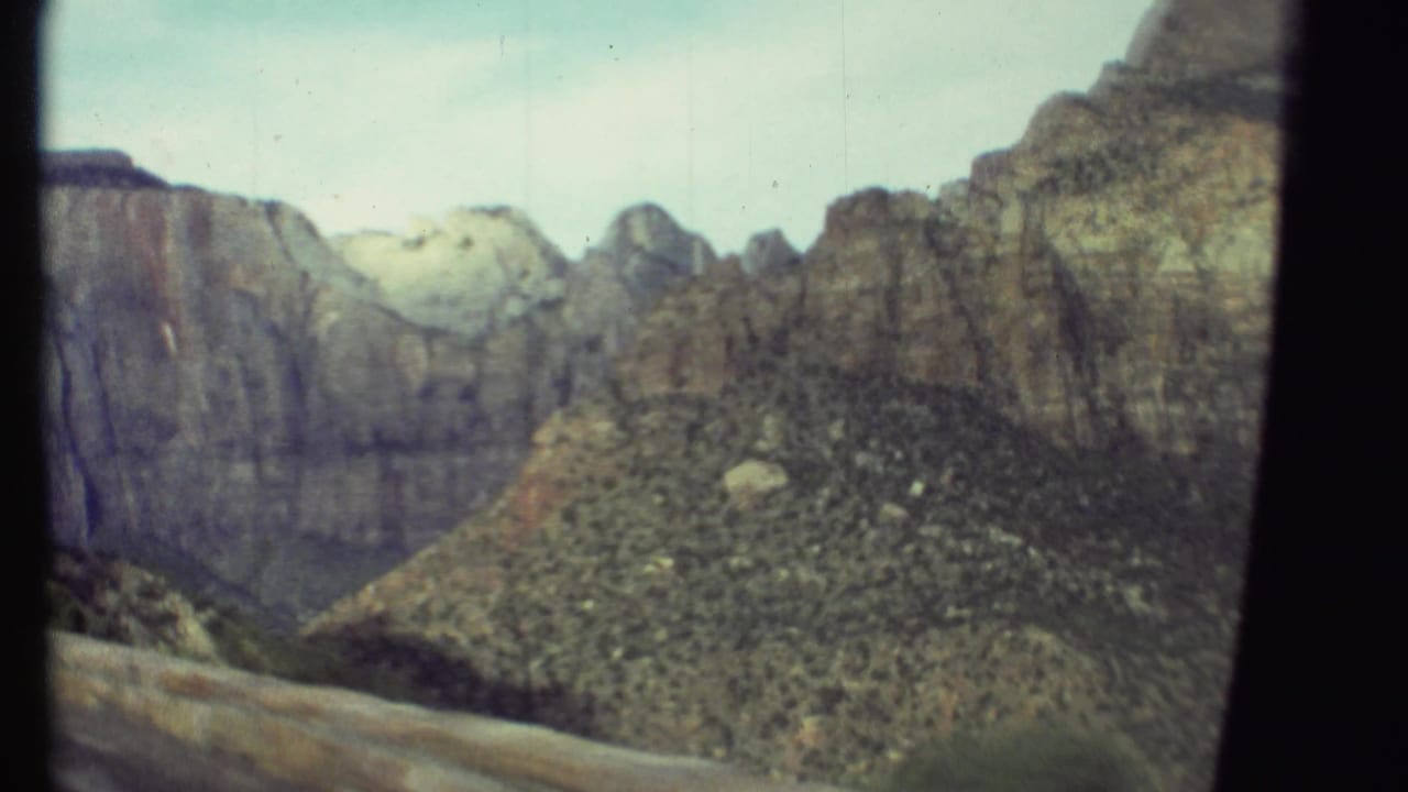Rocky canyon walls and shrub-covered slopes framed by dark vertical film edges.