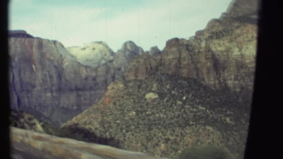 Grand Canyon landscape on 8mm film, with rugged cliff faces, desert vegetation, and dark gate borders visible in the frame.